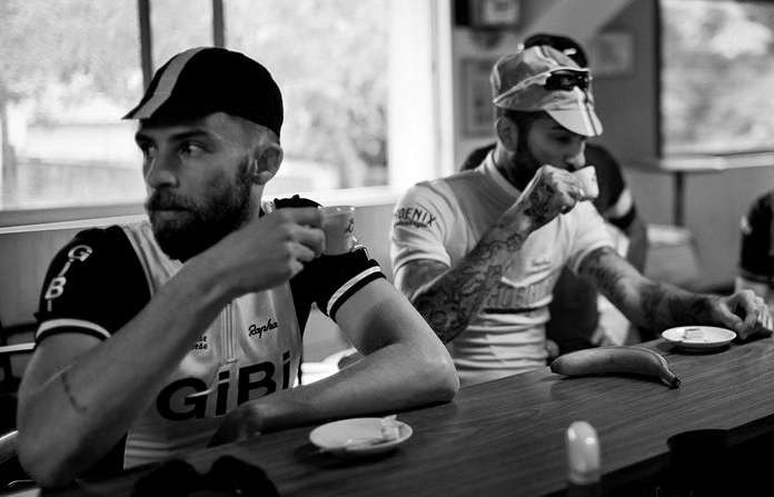 Men pretending to be cyclists pretending to drink coffee and pretending not to notice the camera